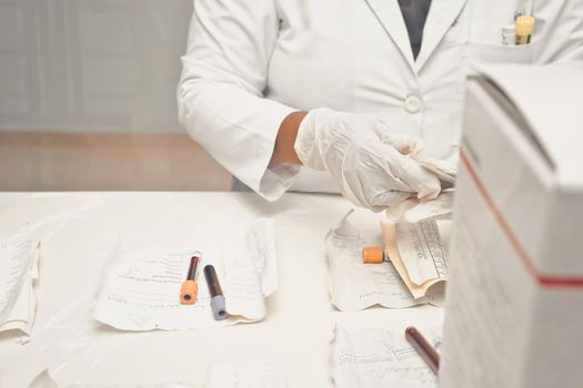 Unrecognizable clinical laboratory worker sorting blood samples in a hospital