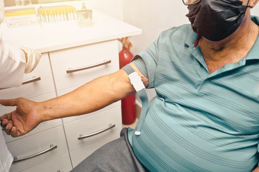 Latino elderly man getting a blood sample in a hospital
