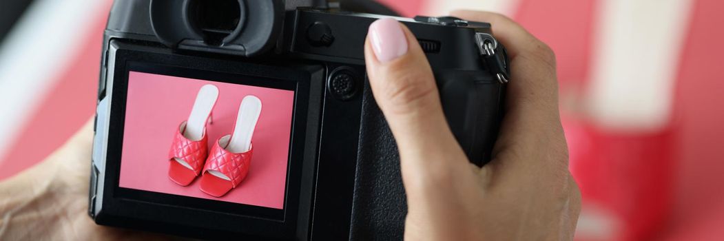 Woman professional photographer taking picture of red trendy shoes