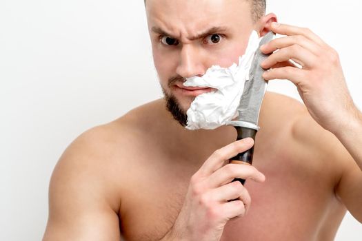 Man shaving beard with knife