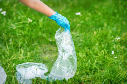 Hand of child cleans the park from plastic debris