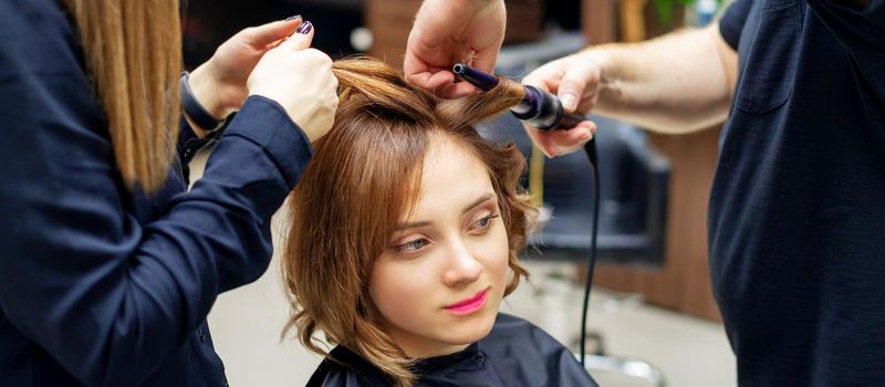 Hairdresser curling long light brown hair