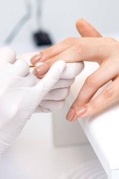 Manicure master applying beige nail polish