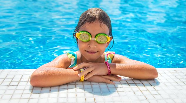 A child with glasses dives into the pool. Selective focus.