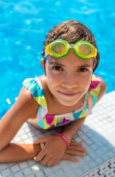 A child with glasses dives into the pool. Selective focus.