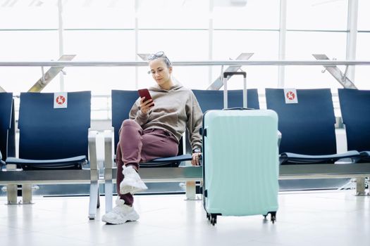 young woman with luggage sitting in the airport waiting room .