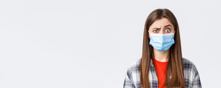 Coronavirus outbreak, leisure on quarantine, social distancing and emotions concept. Confused young woman cant understand what happening, look suspicious or surprised, wear medical mask