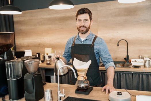 Man barista making filter coffee in cafeteria