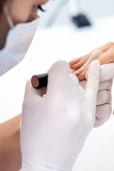 Manicure master applying beige nail polish