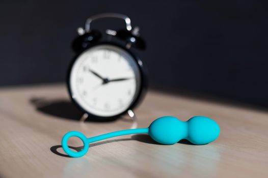 Alarm clock and vibrator on the table. Time for training intimate muscles. Vaginal balls strengthen the pelvic floor muscles for powerful orgasms.