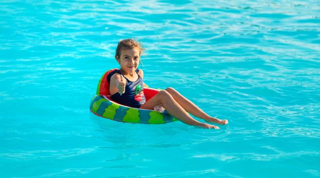 A child in a circle swims in the pool. Selective focus. Kid.