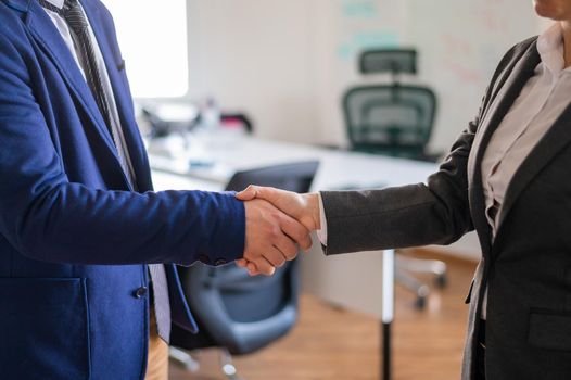 Handshake of unrecognizable business persons as a gesture of a successful deal. Hands of office workers in suits during a greeting. Partnership agreement. Faceless managers.