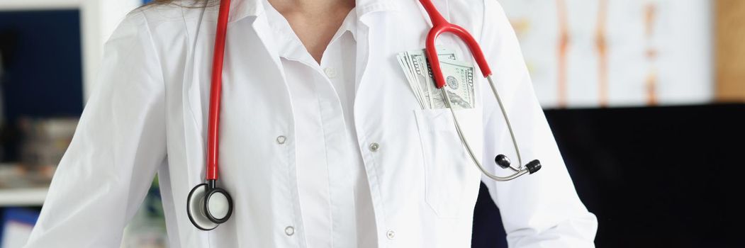 Head doctor in clinic with bunch of money in pocket of medical gown