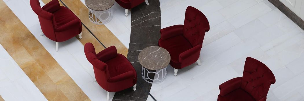 Stylish arm-chairs and tables in hall or hotel lobby