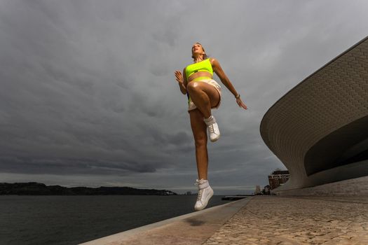 Woman in fitness wear doing jumping workout outdoors.. Sporty girl with fit body in sportswear jump on sky background.
