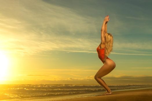 Beautiful girl dancing on the beach over sunset background.