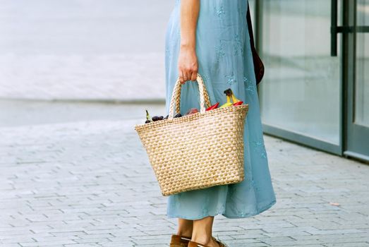 woman in the city walking with straw bag from shopping