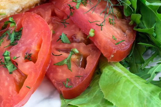 Sliced tomatoes next to lettuce and parsley.