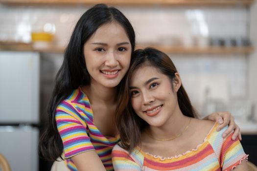 Smiling young lesbian couple standing affectionately together at home