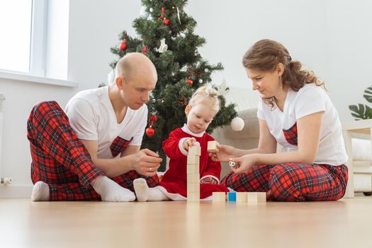 Toddler child with cochlear implant plays with parents under christmas tree - deafness and innovating medical technologies for hearing aid