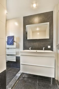 Open shower and sink in black tiled room