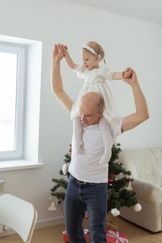 Baby child with hearing aid and cochlear implant having fun with father on christmas tree background. Deaf , diversity and health concept