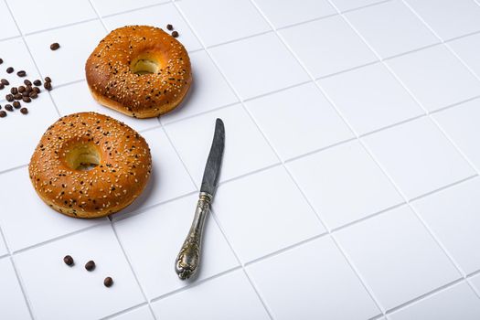 Fresh Bagels with Sesame set, on white ceramic squared tile table background, with copy space for text