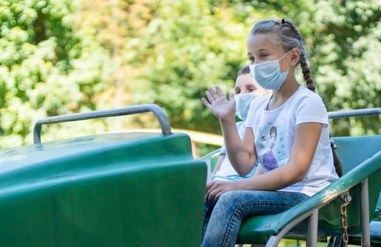 children in medical masks ride the attraction