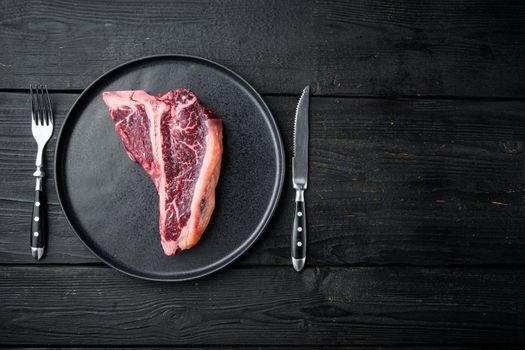 Sirloin beef meat marbled steak, T bone cut, on black wooden table background, top view flat lay, with copy space for text