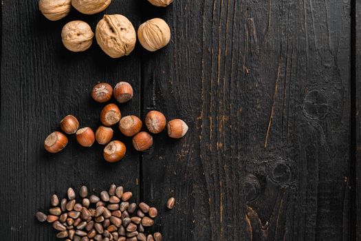 Heap or stack of hazelnuts, on black wooden table background, top view flat lay, with copy space for text