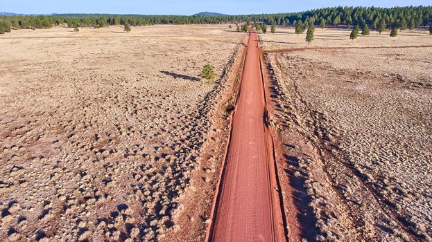 Red dirt road straight through desert plains from aerial view