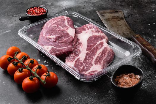 Beef steak in vacuum packing. Market Chuck Eye Roll, on black dark stone table background