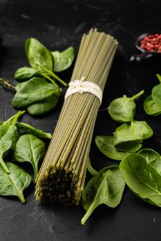 Raw dry green spaghetti with spinach, on black dark stone table background