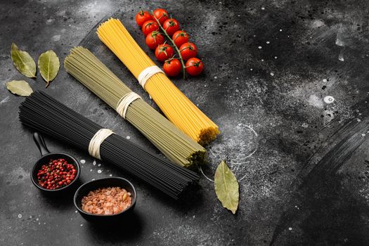Colored dry italian pasta, on black dark stone table background, with copy space for text