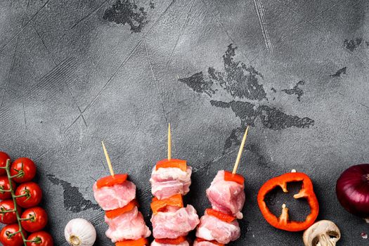 Skewer with raw kebab pork meat and onion, top view flat lay, with copy space for text, on gray stone table background