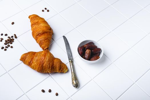Fresh croissants on table set, on white ceramic squared tile table background, with copy space for text