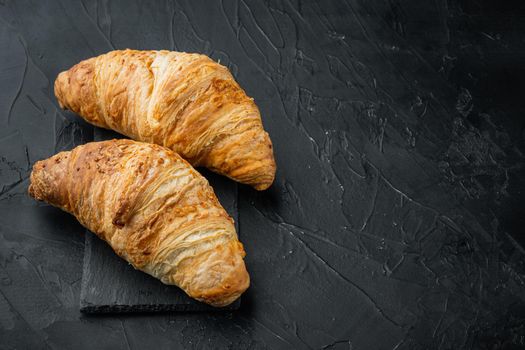 Crispy fresh croissants, on black stone background, with copy space for text