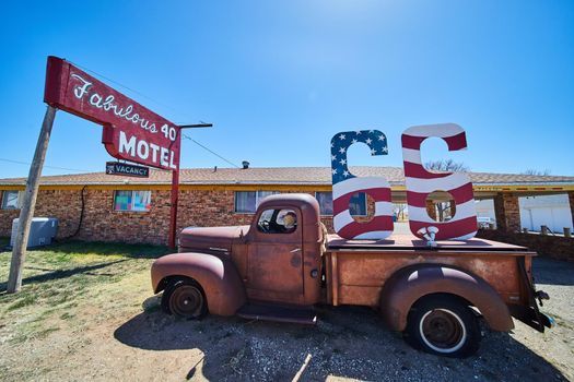 Old truck on Route 66 with American Flag pattern in sign by motel