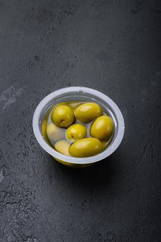 Green olives in oil set, on black dark stone table background, with copy space for text