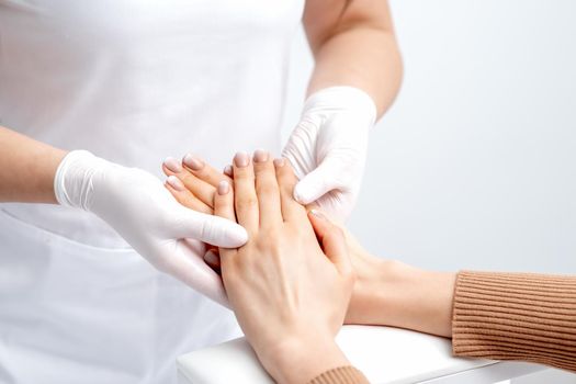 Manicurist massaging female hand with manicure
