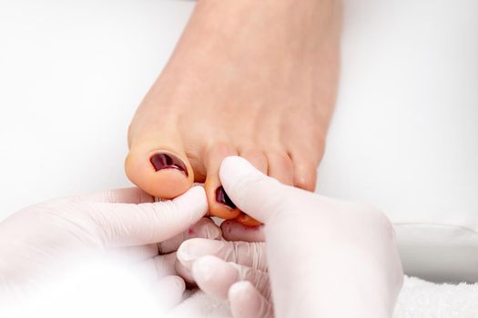 Manicure master holds female toenail