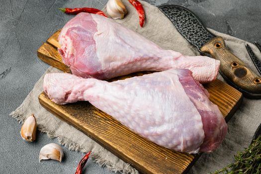 Raw organic turkey legs with ingredients for cooking, on wooden cutting board, on gray stone table background