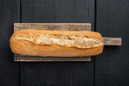 Baguette, on black wooden table background, top view flat lay