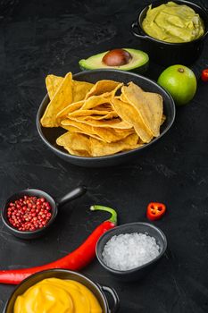 Mexican crispy snack, nachos chips and cheese guacamole avocado sauce, on black background