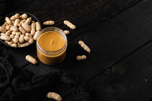 Fresh made creamy Peanut Butter, on black wooden table background, with copy space for text