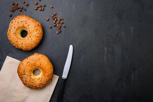 Fresh Bagels with Sesame set, on black dark stone table background, top view flat lay, with copy space for text