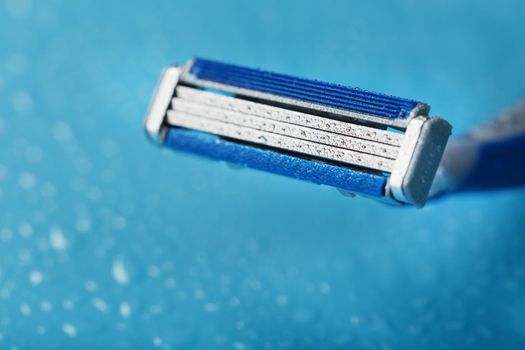 Razor blades on a blue background with drops of icy water