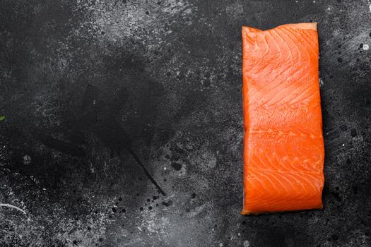 Raw Fillet of salmon, on black dark stone table background, top view flat lay, with copy space for text