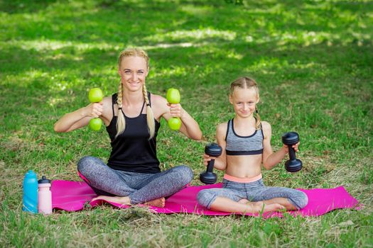 Young woman and girl are training with dumbbells