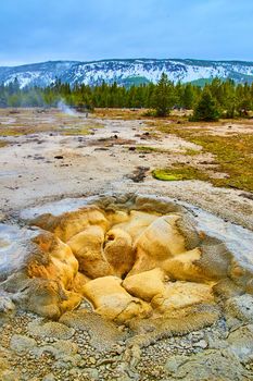 Stunning geyser opening in Yellowstone surrounded by winter hills